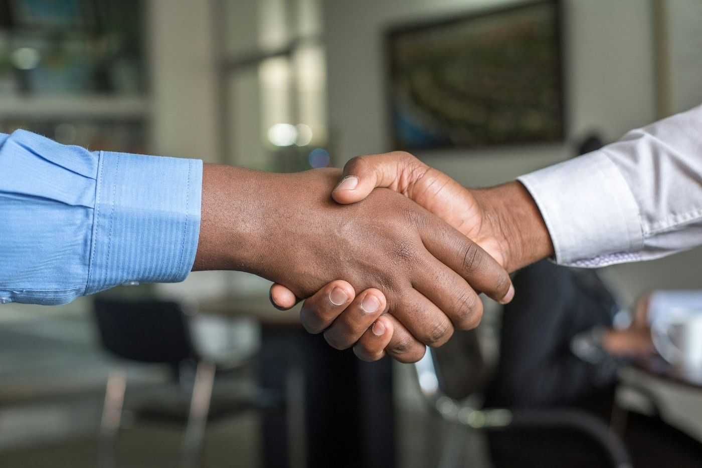 Two people shaking hands across a desk, the signed client that law firm marketing exists to produce