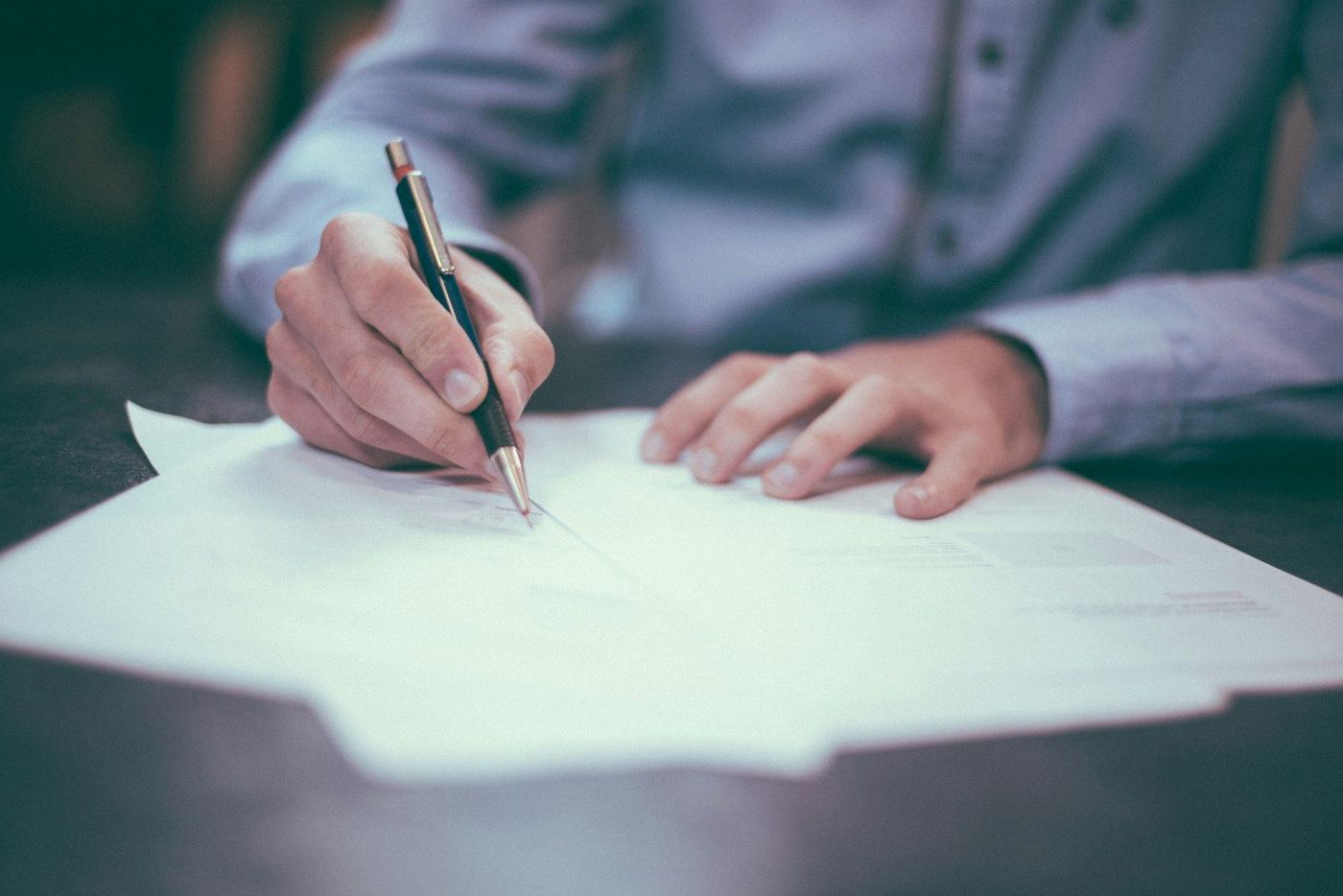 A person signing a document at a desk, the signed case law firm marketing results are measured by